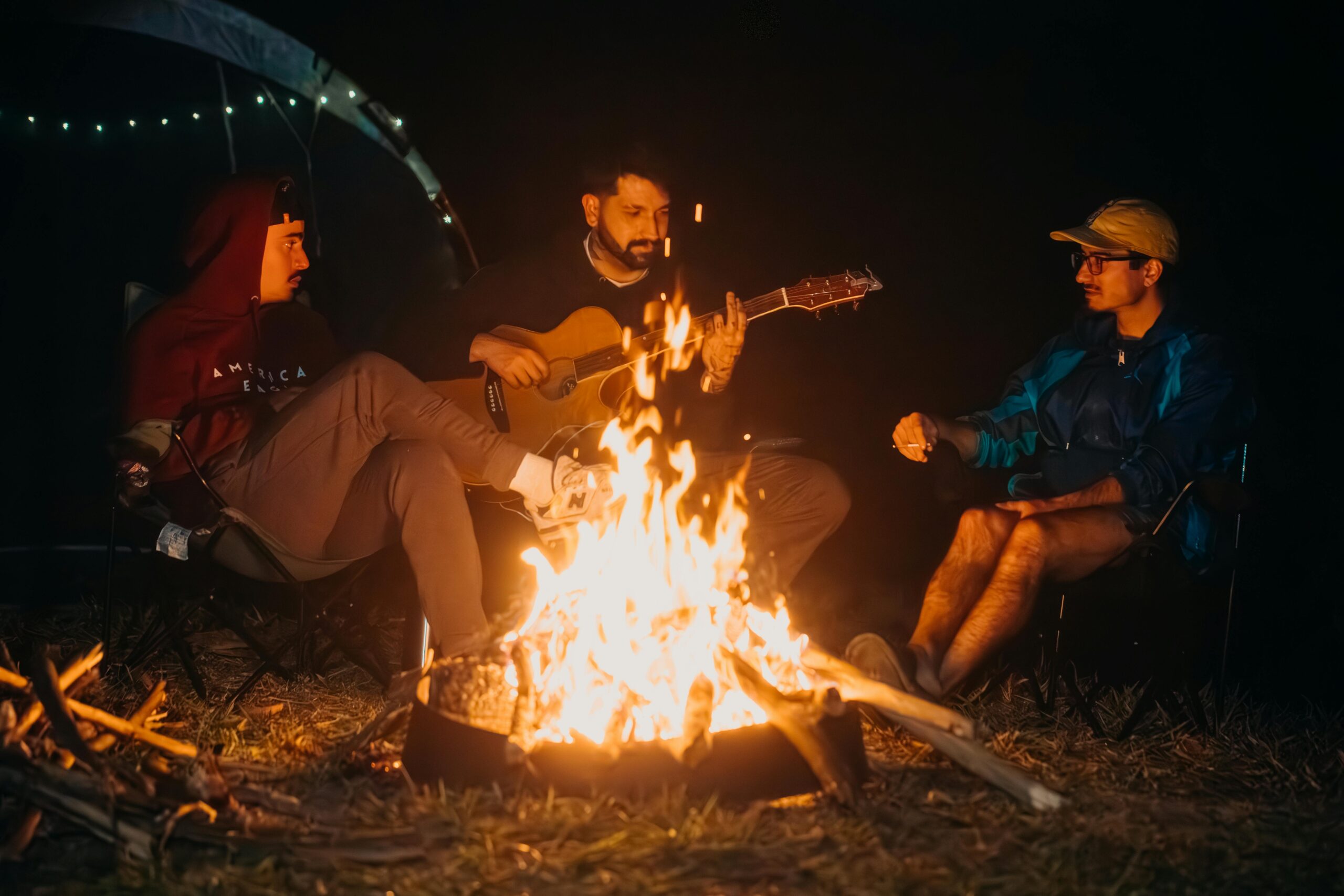 Three friends enjoy a night by the campfire with guitar music in Natividade da Serra, Brazil.